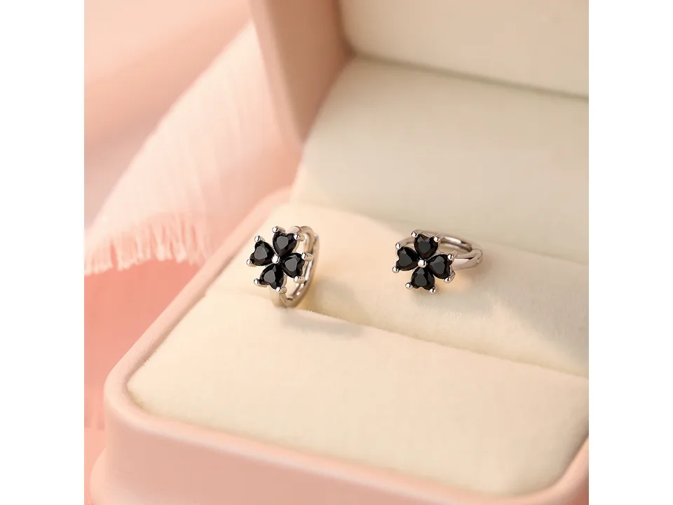 Silver clover hoop earrings with black stones displayed in a jewelry box.