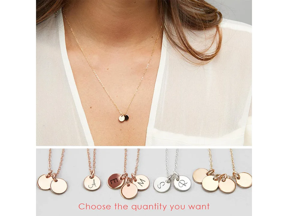 A woman wearing a gold necklace with two small disc pendants.