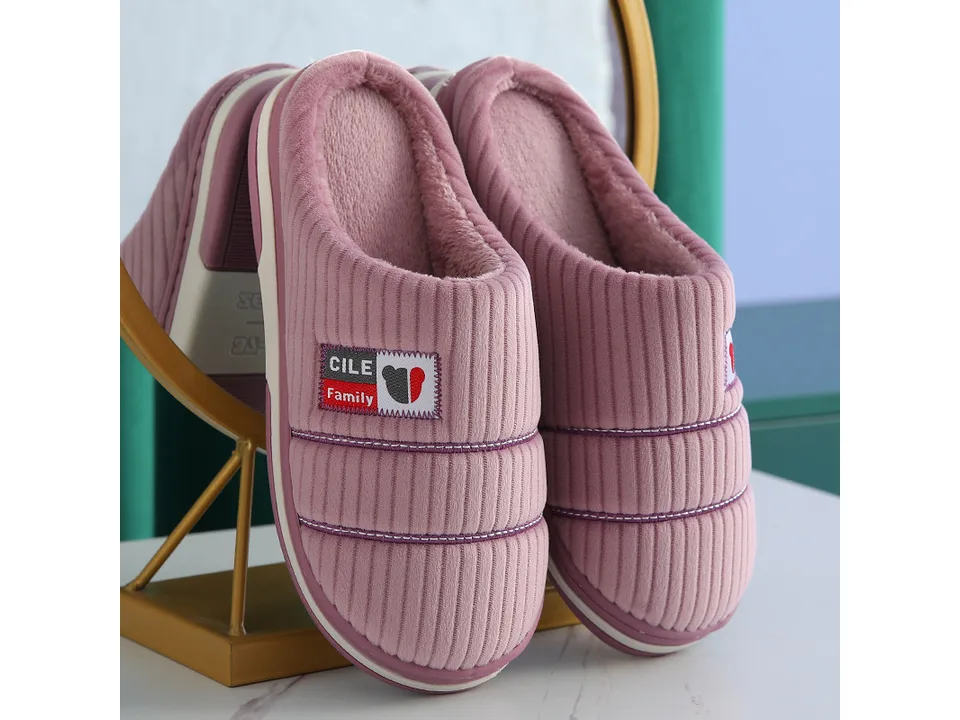 A pair of purple corduroy house slippers with a small logo patch.