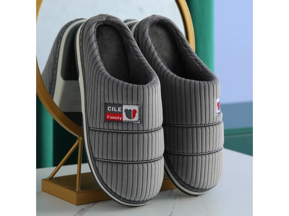 A pair of grey corduroy house slippers with a small logo patch.