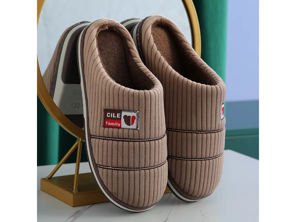 A pair of brown corduroy house slippers with a small logo patch.