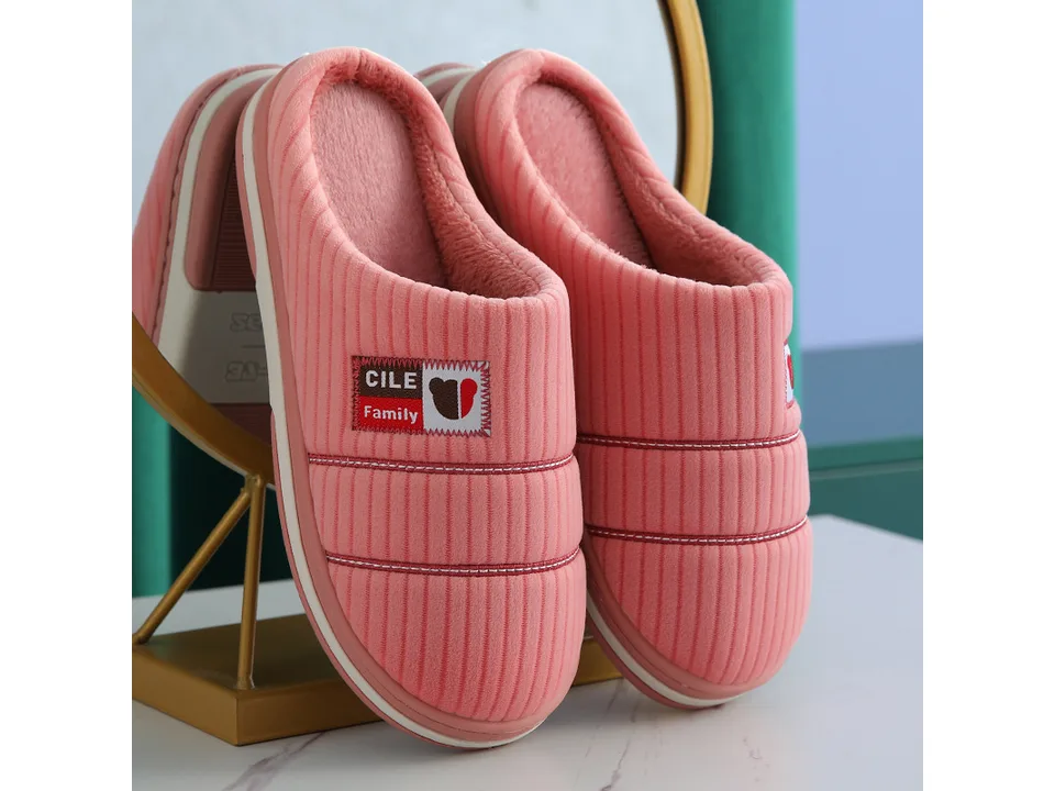 A pair of pink corduroy house slippers with a small logo patch.