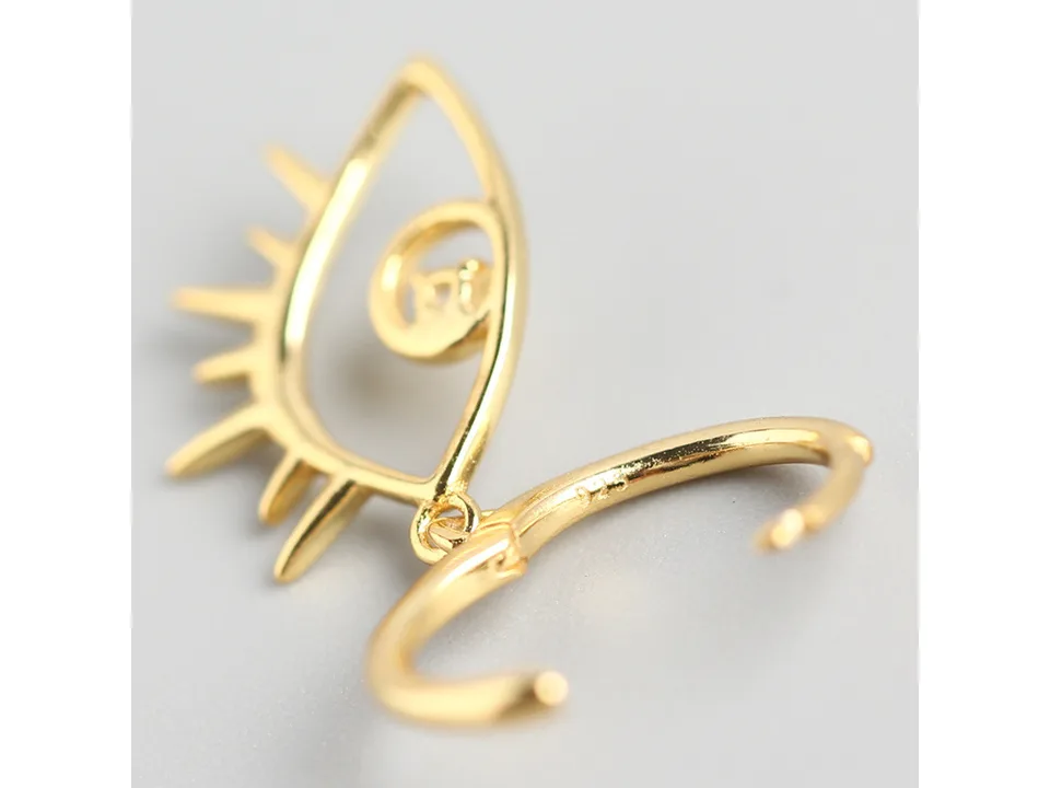 Close-up of a single gold evil eye hoop earring.