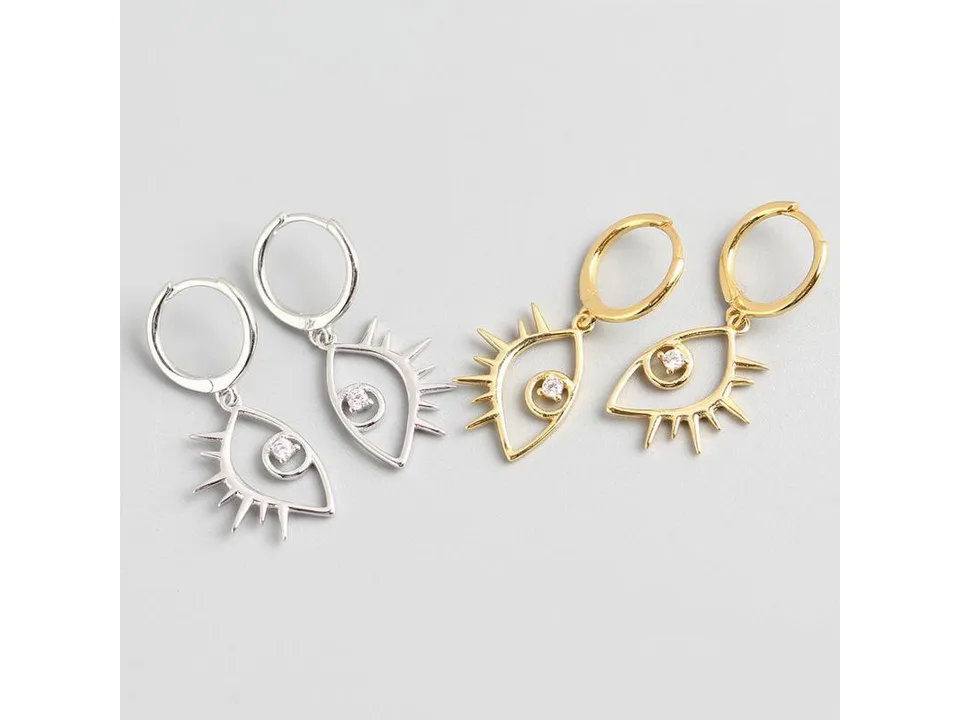 A pair of silver and a pair of gold evil eye hoop earrings.