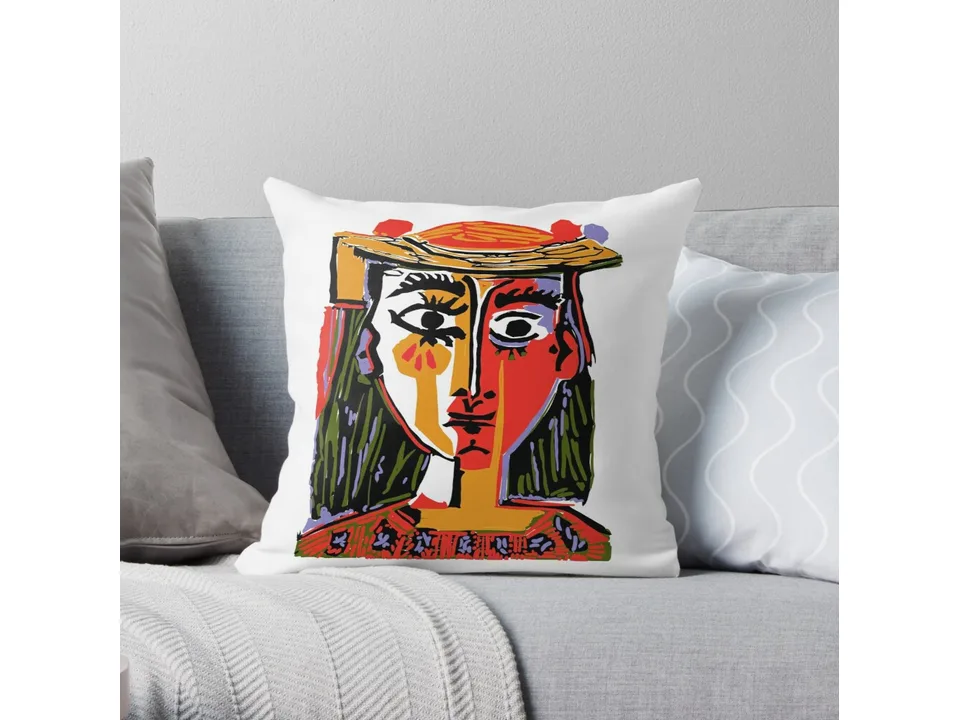 Throw pillow with a colorful abstract portrait design on a white background on a grey sofa.