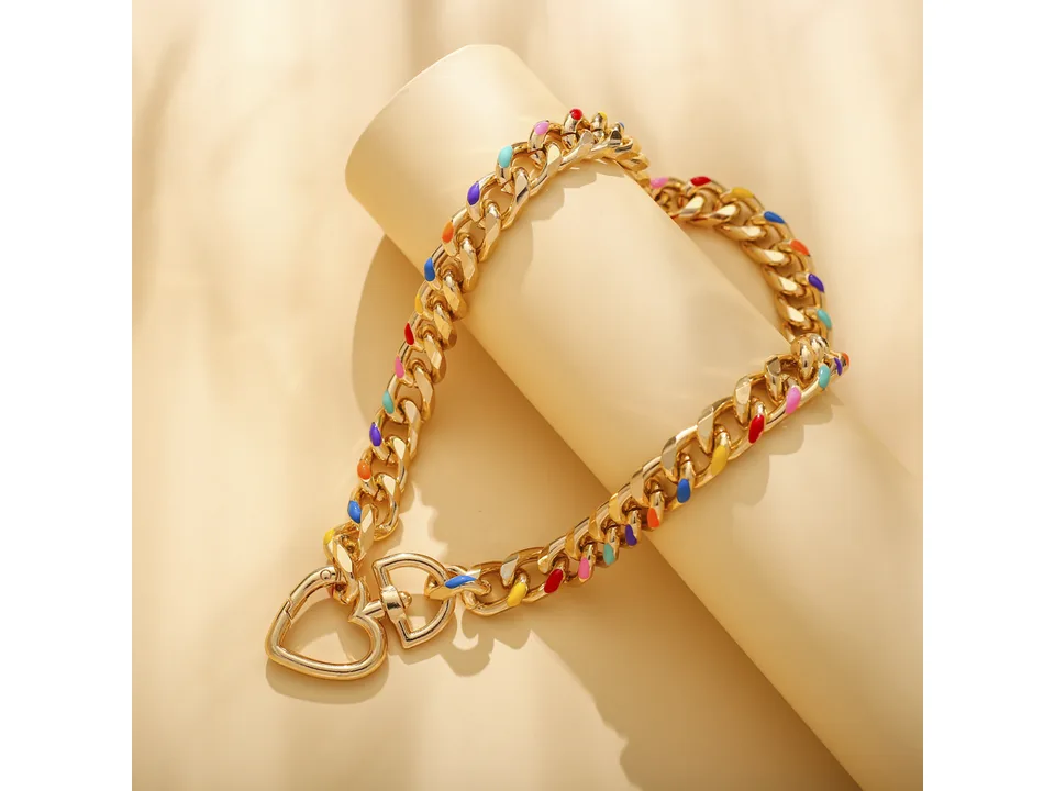 Close-up of the gold chain necklace with colorful accents and heart pendant.