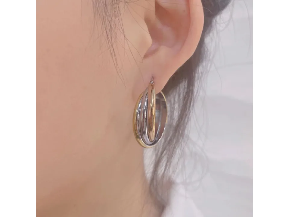 A close-up of a person wearing the three-ring overlapping gold earrings.