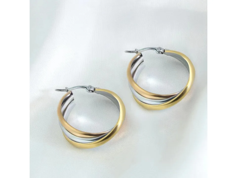 A pair of three-ring overlapping gold earrings resting on a white fabric surface.