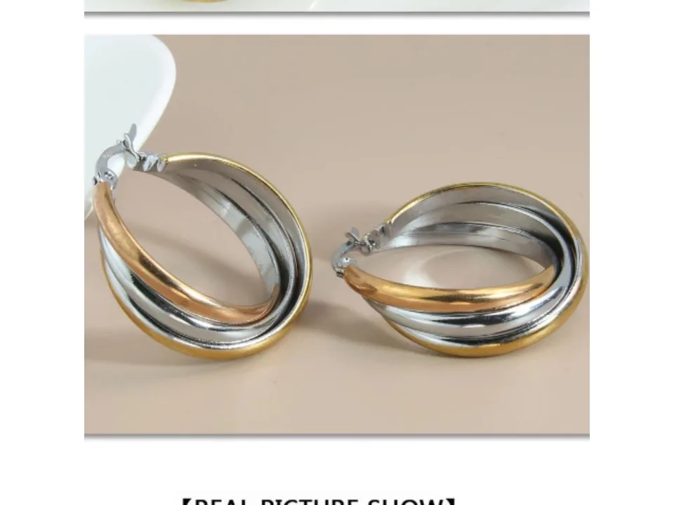 A pair of three-ring overlapping gold earrings on a neutral background.