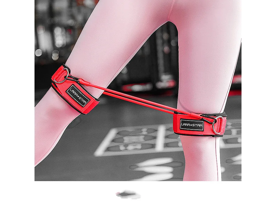 Person wearing red leg resistance bands on their thighs while standing.