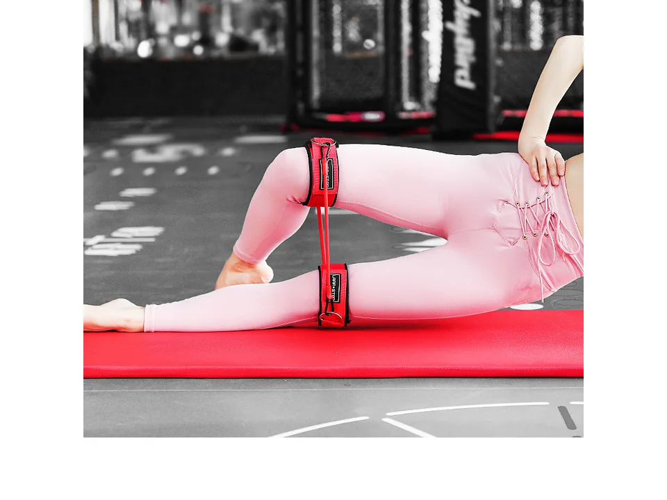 Person lying on a mat using red leg resistance bands for exercise.