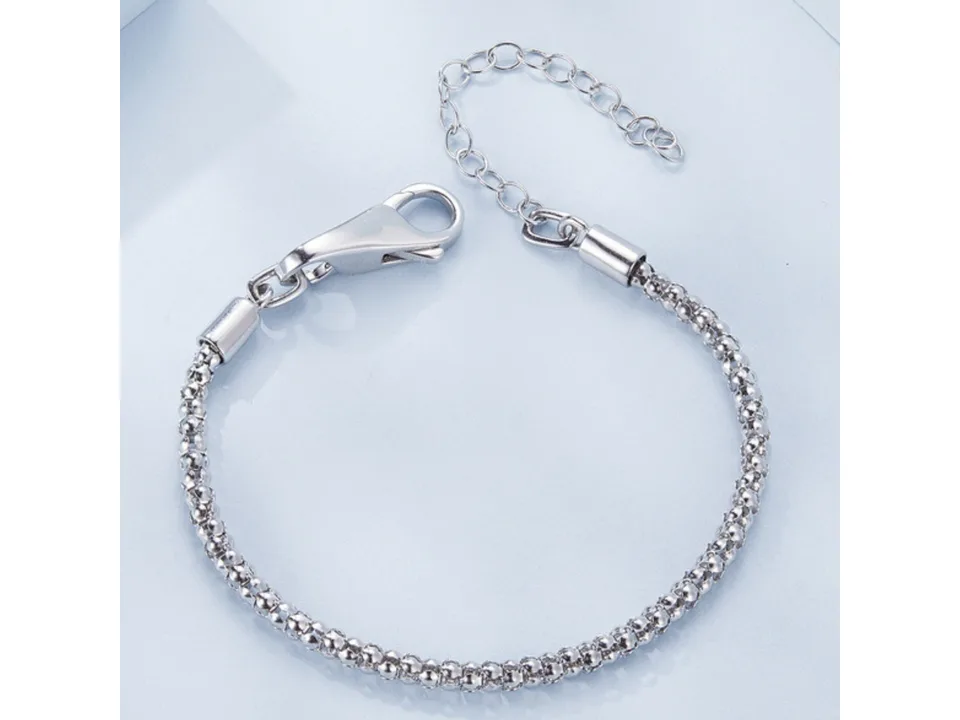 A silver chain bracelet with a lobster clasp on a light blue background.