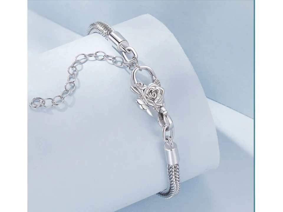 A silver chain bracelet with a rose-shaped lobster clasp on a display stand.