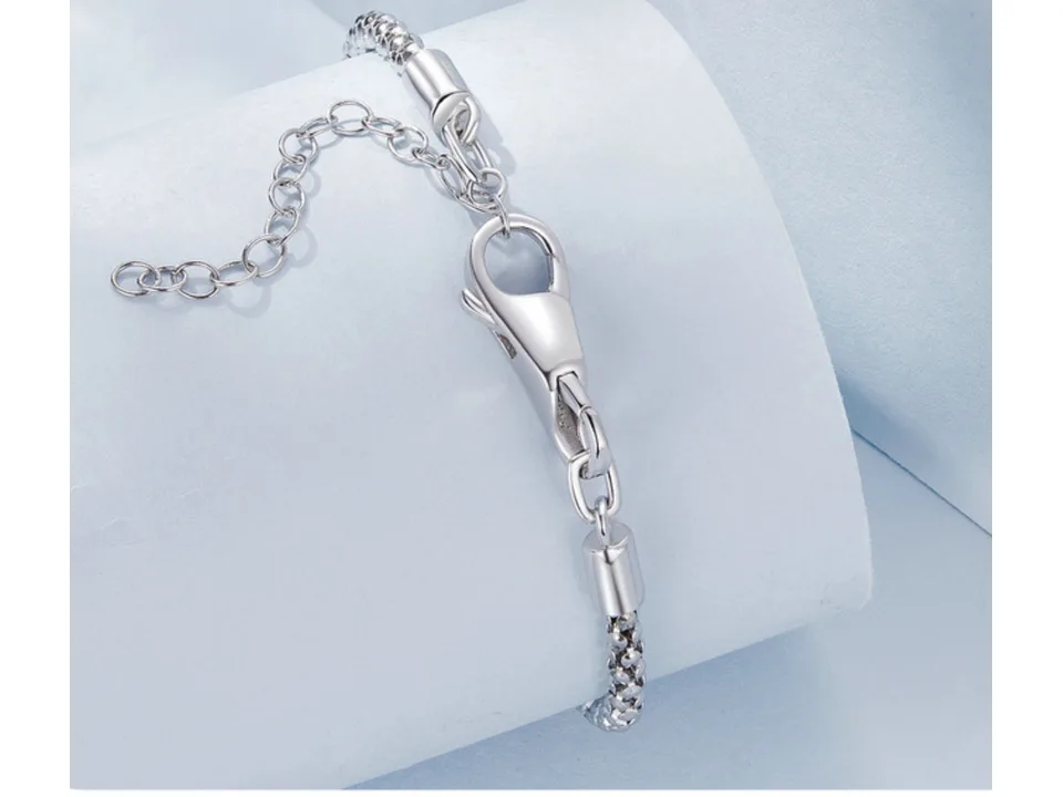 Close-up of a silver bracelet clasp and chain on a curved display stand.