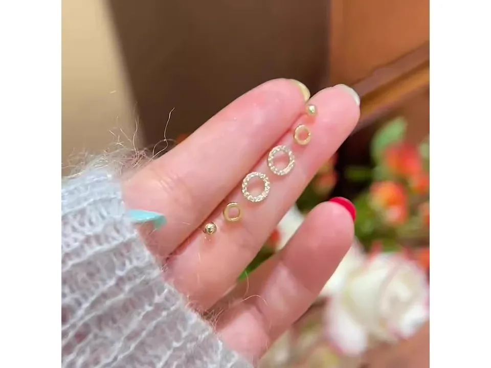 A hand holding all six pieces of the geometric circle earring set.