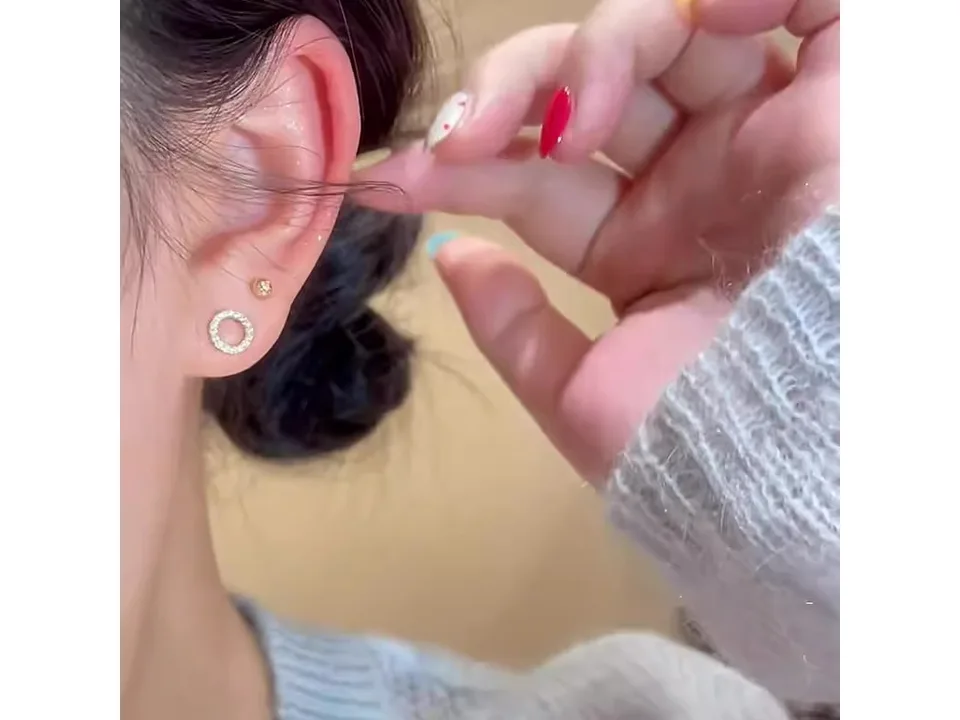 Close-up of a person wearing a small circle earring in their ear.