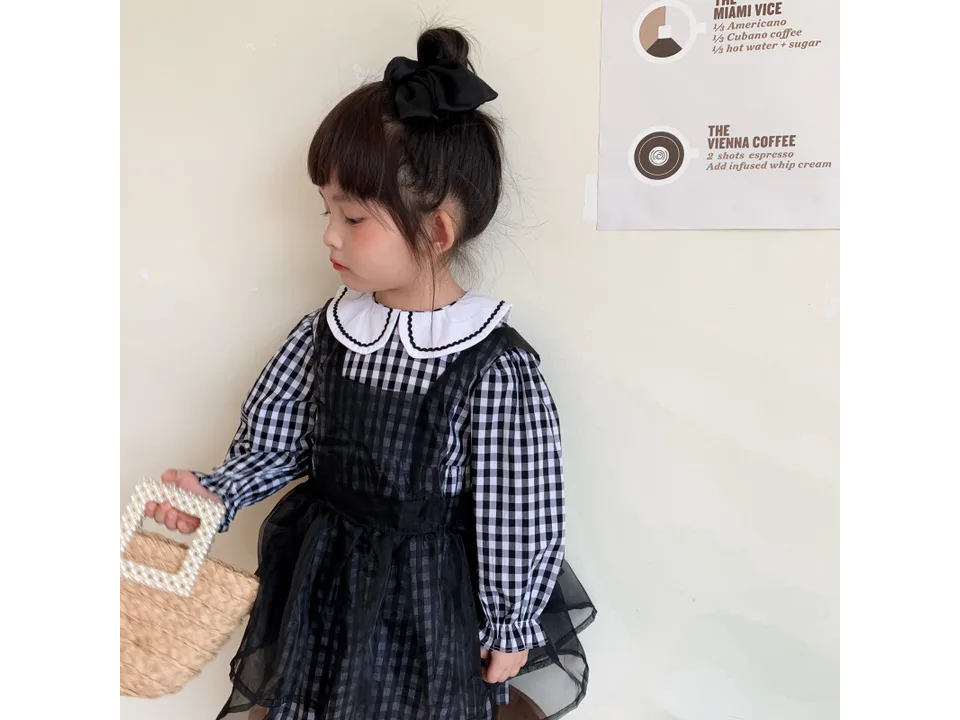 Young girl wearing a black and white plaid dress with a Peter Pan collar