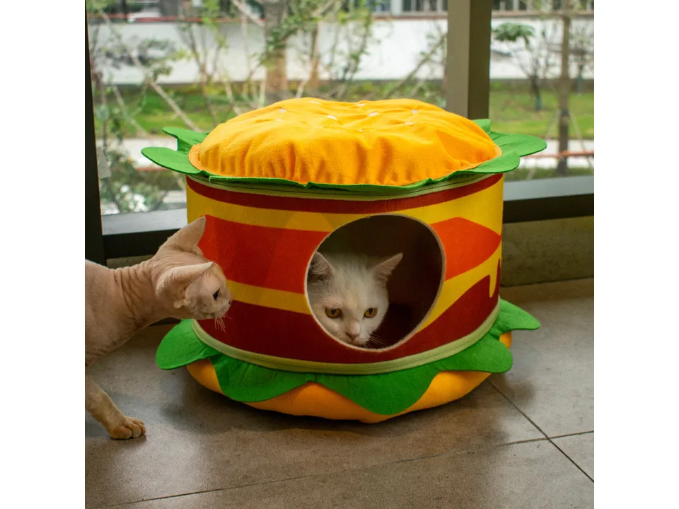 A cat sitting inside a burger-shaped pet bed.