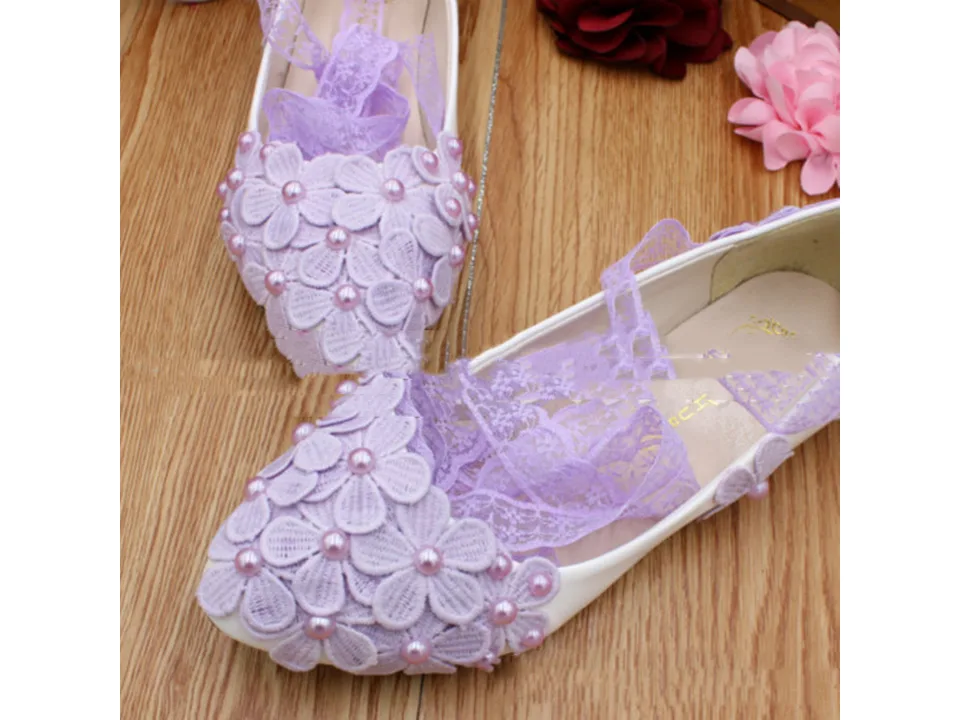 Close-up of lavender floral lace-up flats on a wooden surface.