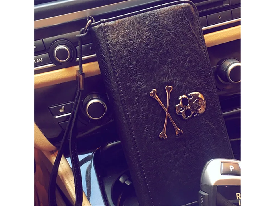 Black skull motif wallet with wrist strap resting on a car center console.