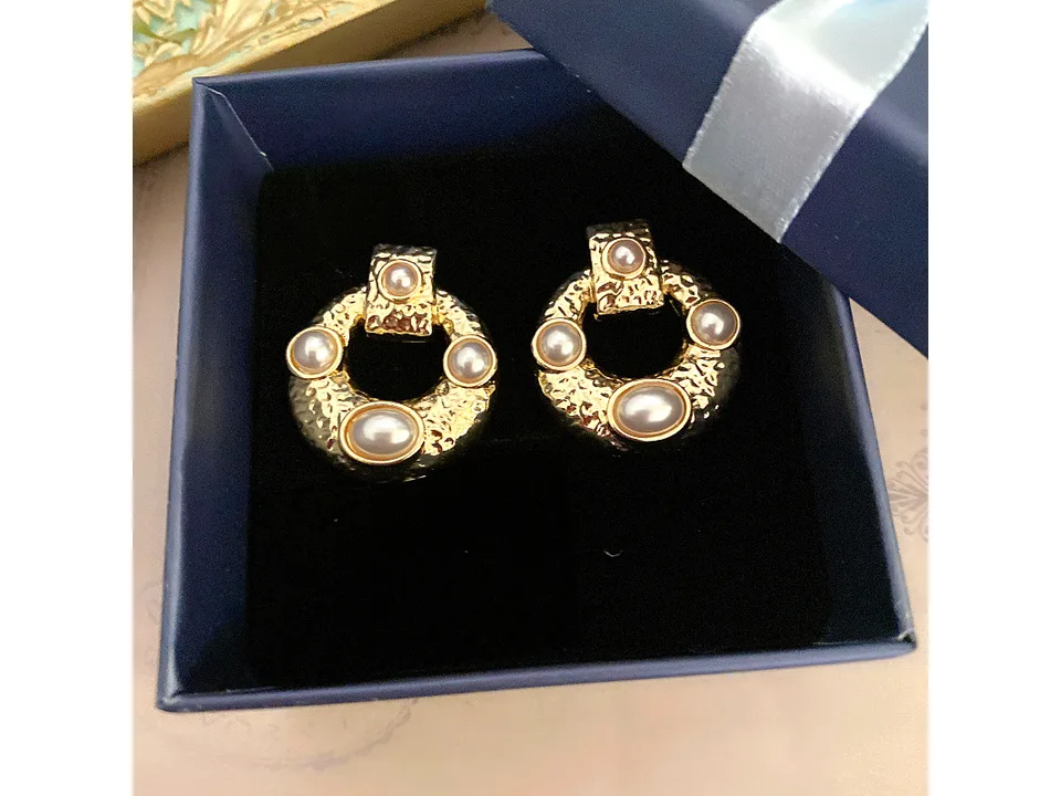 The gold and pearl hoop earrings inside a blue gift box.
