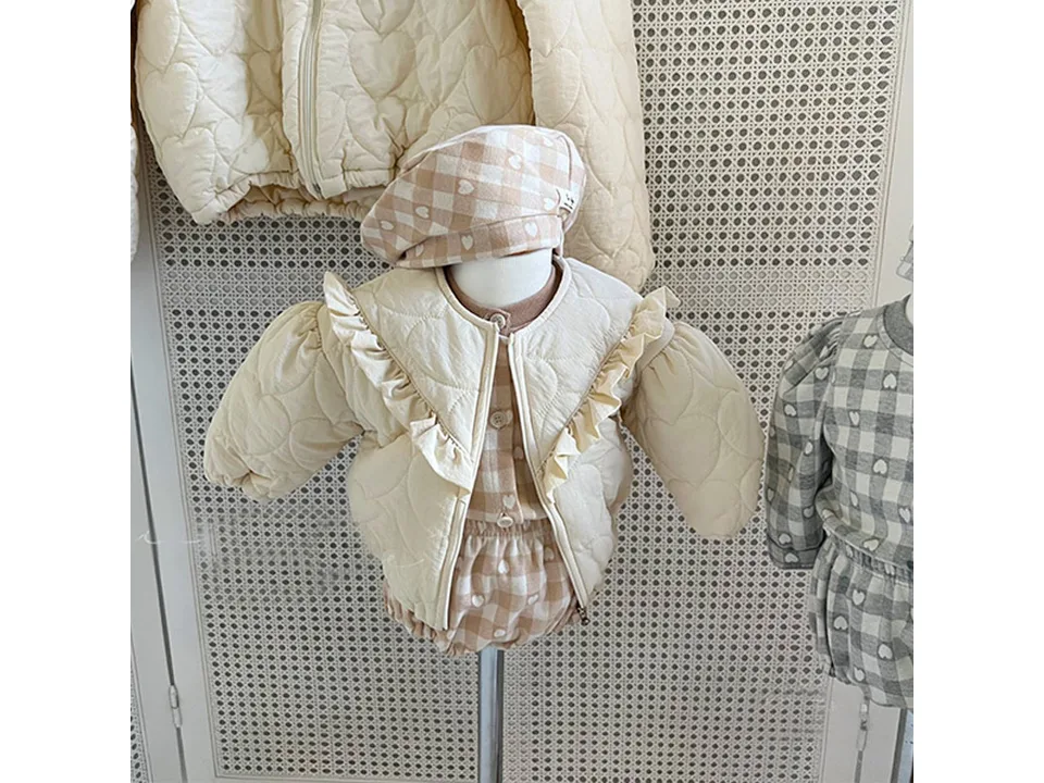 Close-up of the cream quilted jacket with ruffle detail on a mannequin.
