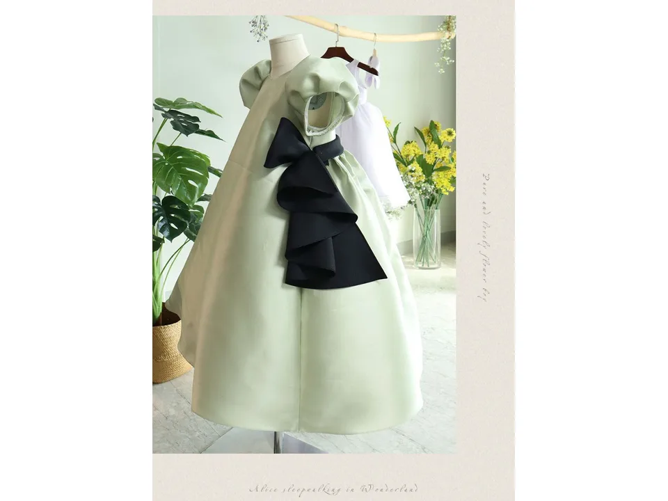 A light green puff-sleeve dress with black bows displayed on a mannequin.