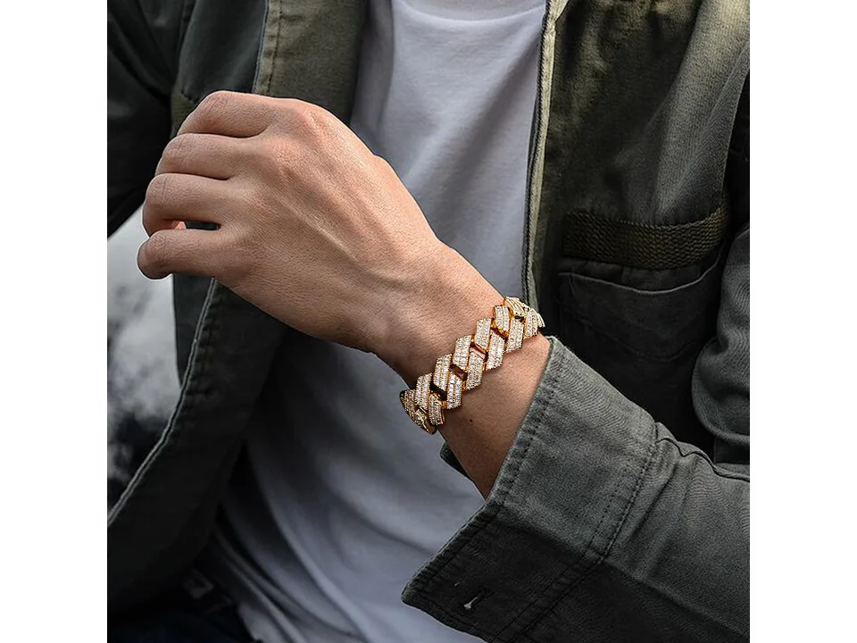A person wearing a gold Cuban link bracelet on their wrist.