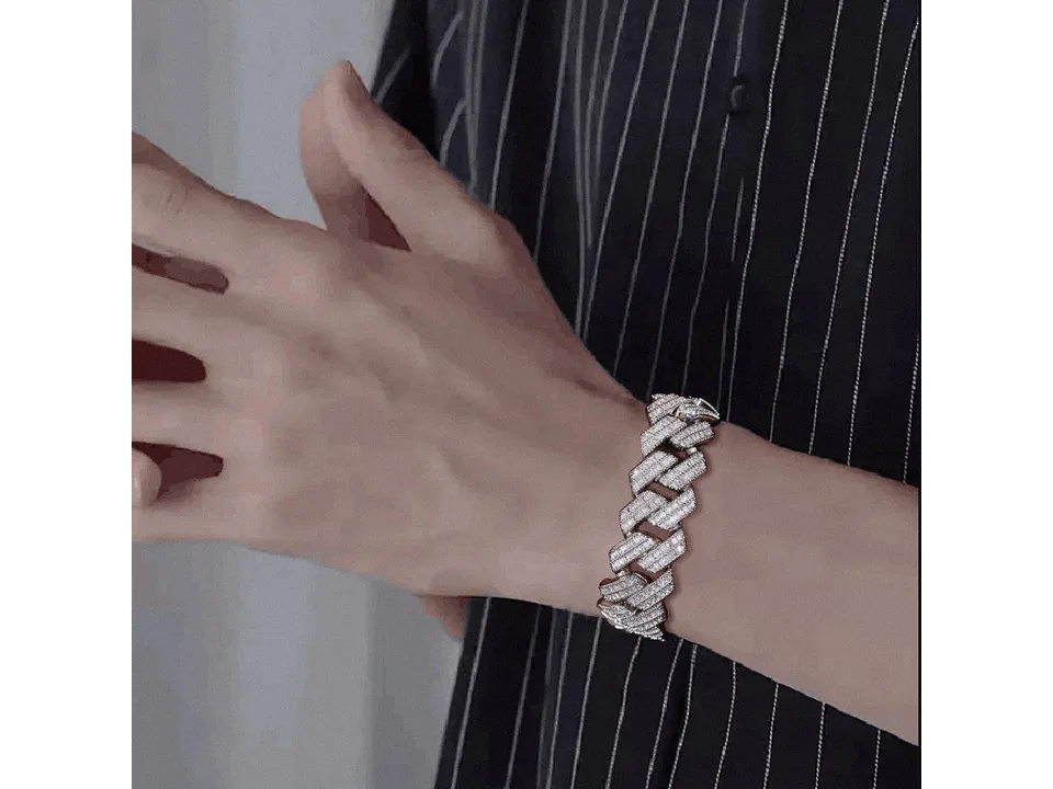 A person wearing a silver Cuban link bracelet on their wrist.
