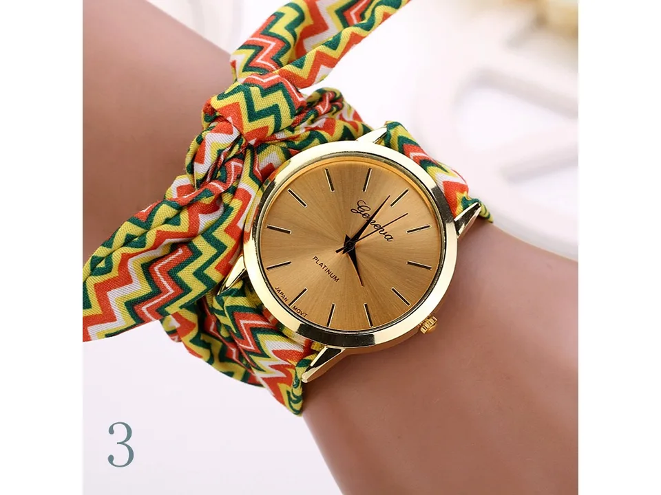 A woman wearing a gold-faced watch with a colorful chevron fabric strap on her wrist.