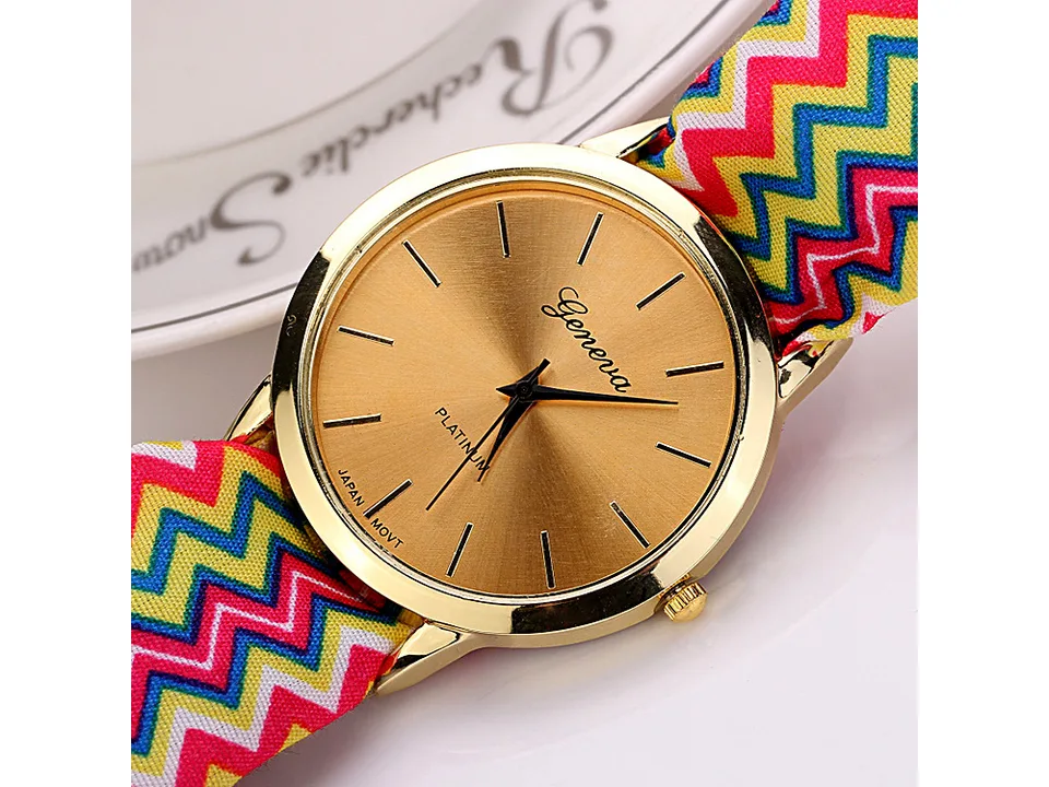 Close-up of a gold-faced watch with a colorful chevron fabric strap.