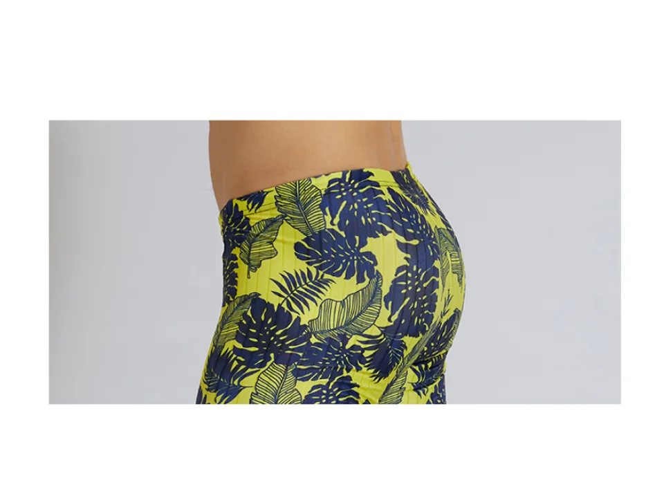 Side view of a man wearing leaf-patterned compression swim jammers.
