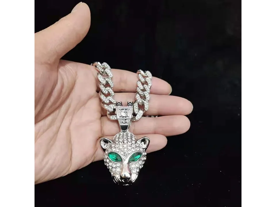Silver leopard head pendant necklace held in a hand.