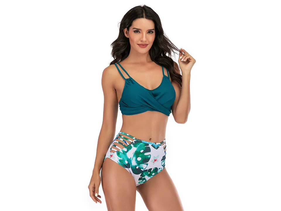 A model wearing a teal bikini top and a high-waisted tropical print bikini bottom.