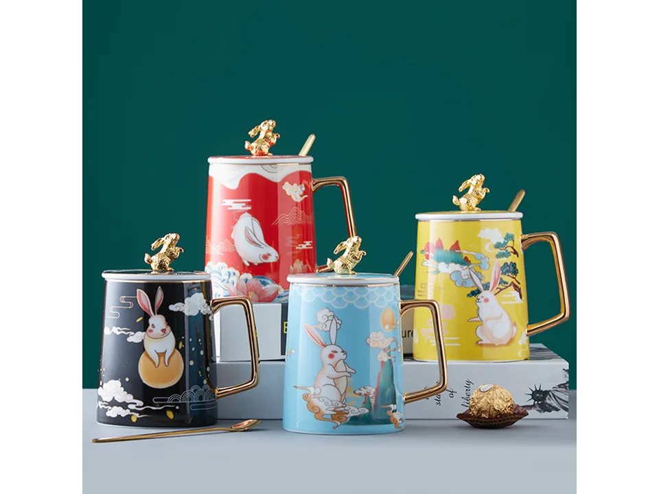 Four ceramic rabbit mugs in different colors with gold lids and spoons.