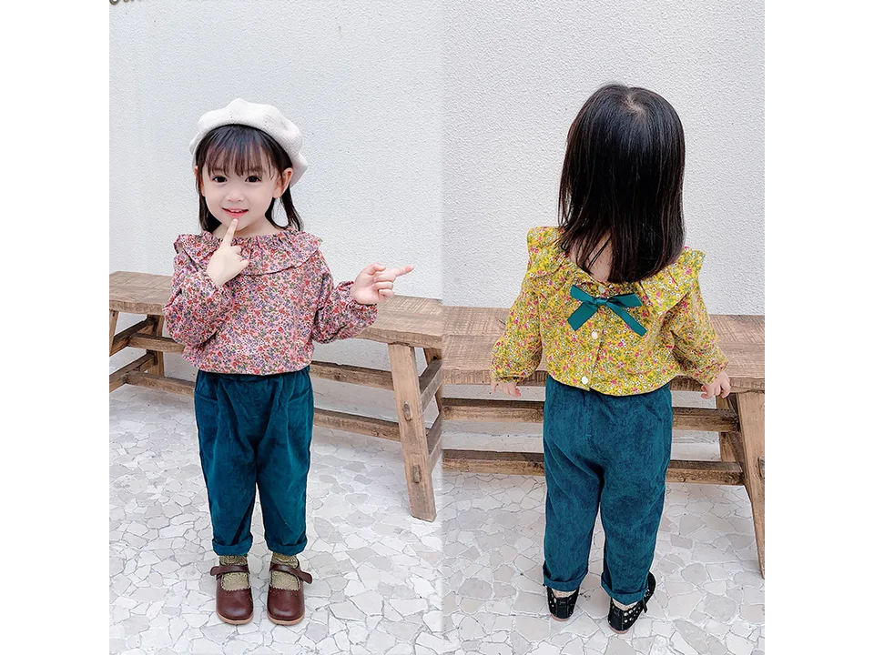 Front and back view of a girl wearing a floral blouse and dark green trousers.