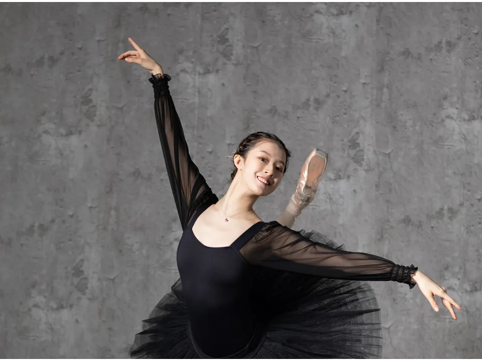 Ballerina in a black leotard with sheer sleeves performing a dance pose.