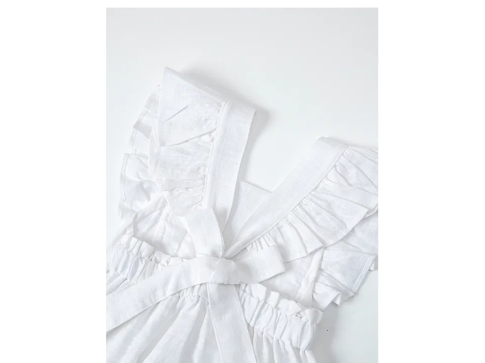 Close-up of the white dress showing ruffled straps and a bowknot detail.