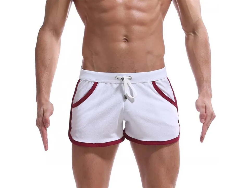Front view of a man wearing white athletic beach shorts with red trim and a drawstring.