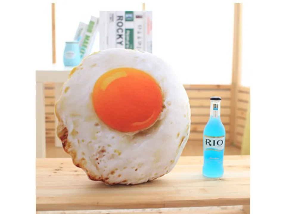 A fried egg shaped plush pillow on a wooden table.