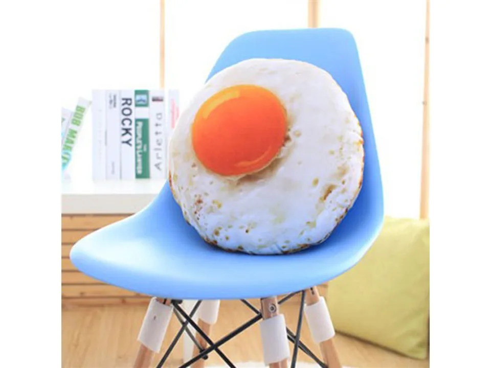 A fried egg shaped plush pillow resting on a blue chair.