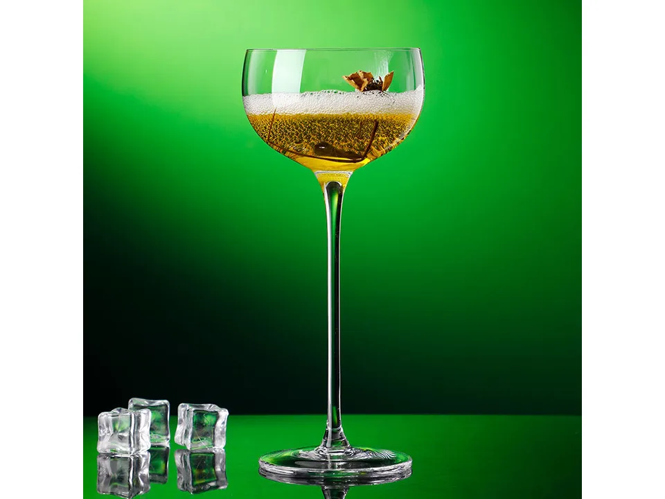 A stemmed cocktail glass filled with an amber-colored drink, garnished with a dried flower.
