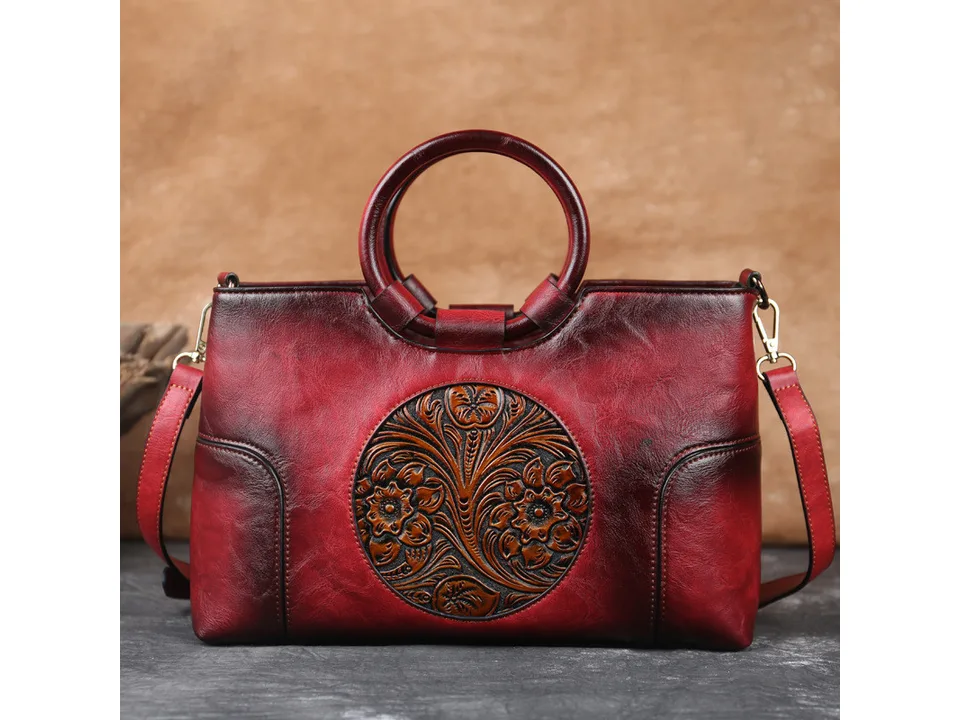 Red vintage-style handbag with a round handle and floral embossed circular design.