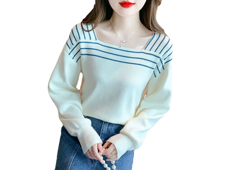 A woman wearing a white square neck sweater with blue striped shoulder details.