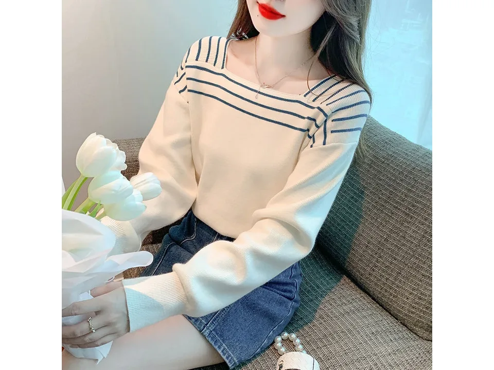 A woman wearing a white square neck sweater with blue stripes, holding a bouquet of white tulips.