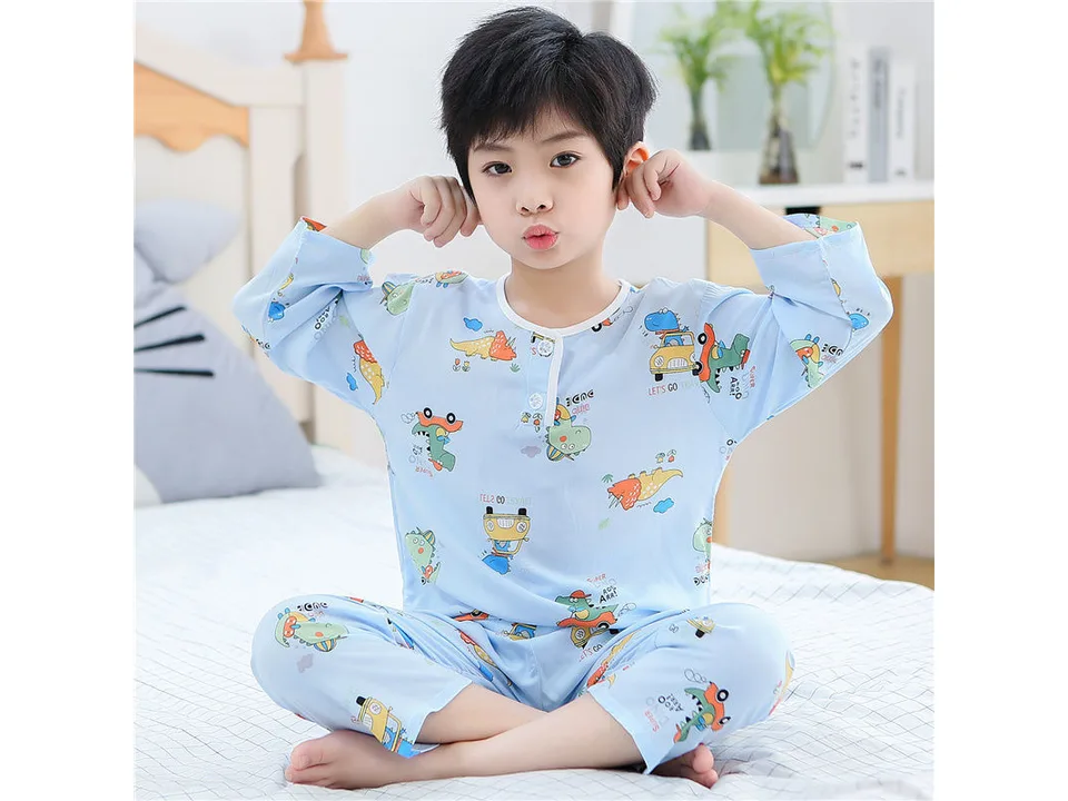 A young boy wearing a light blue long-sleeve pajama set with a dinosaur print.