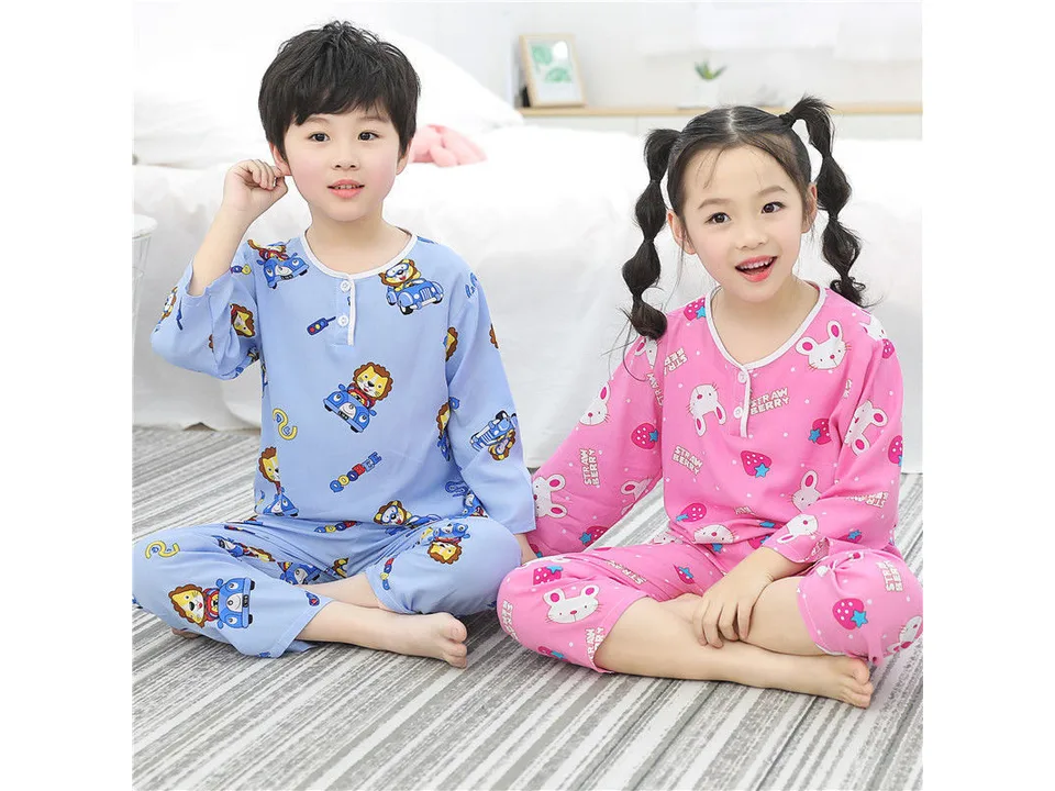 A boy and a girl sitting together wearing different long-sleeve pajama sets.