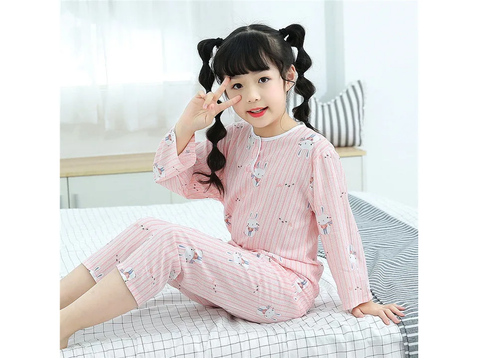 A young girl wearing a pink long-sleeve pajama set with a rabbit print.