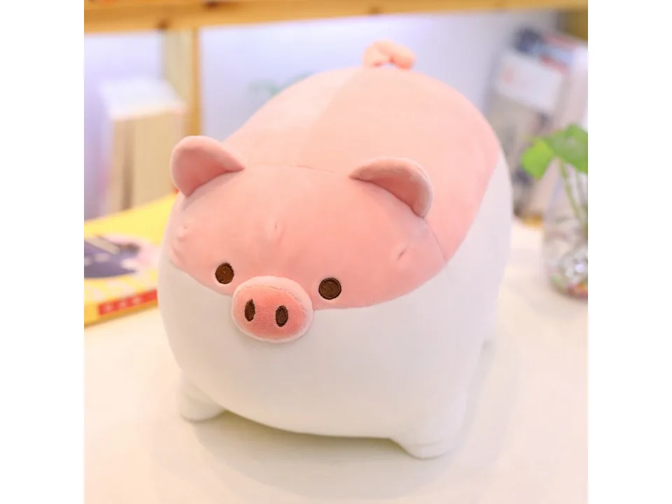 A soft pink and white pig plush toy sitting on a table.