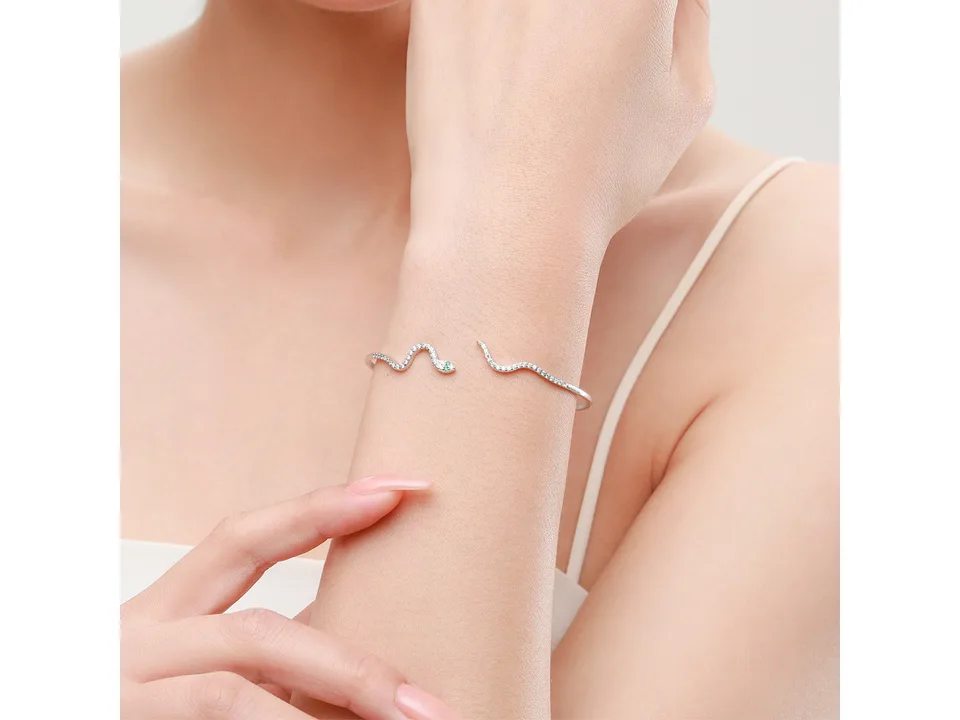 A silver snake-shaped open cuff bracelet worn on a woman's wrist.